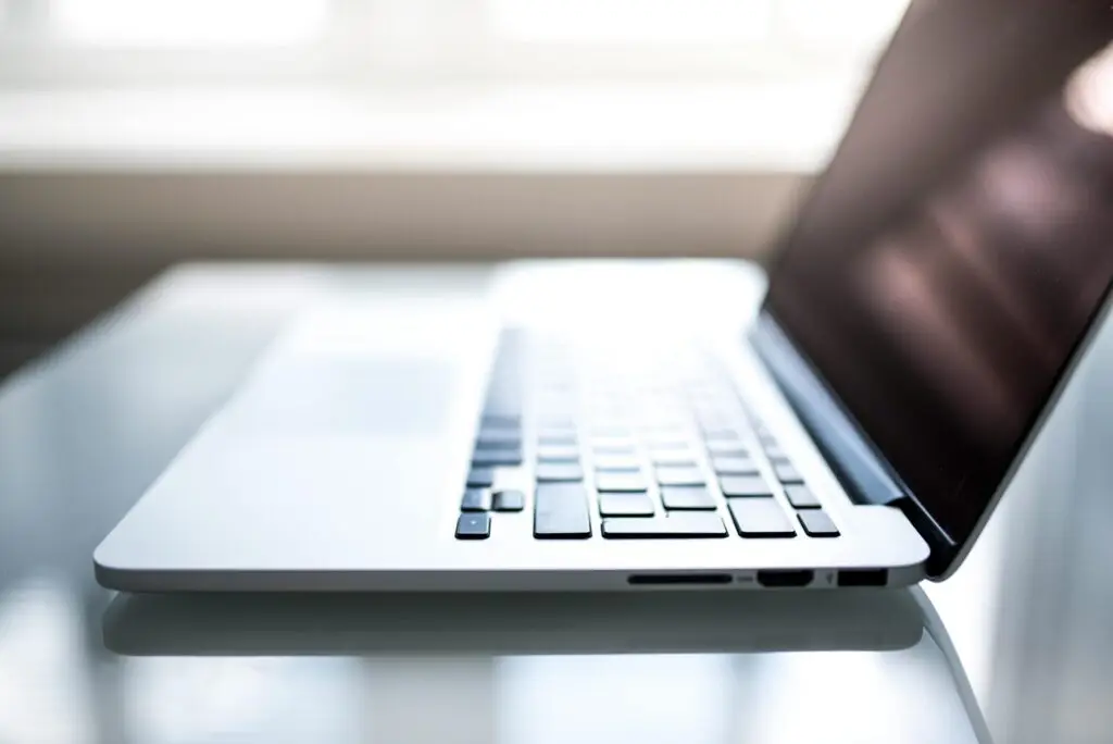 Free Elegant side view of a laptop on a glossy table with natural lighting indoors. Stock Photo